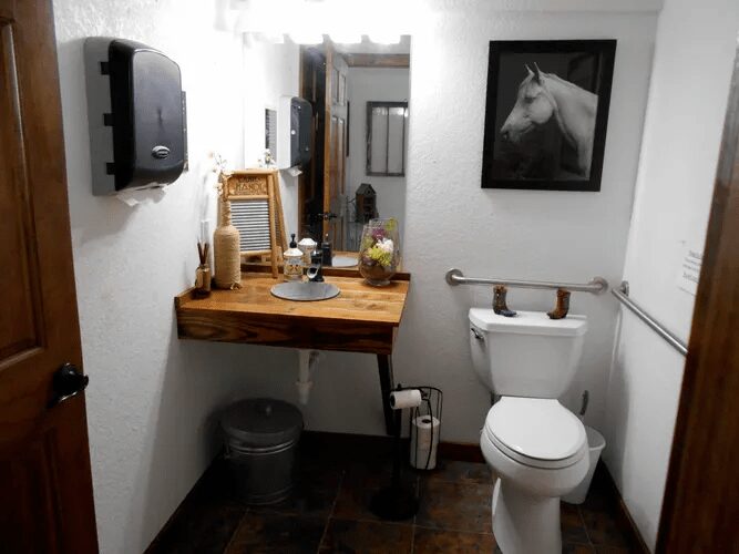 A white and wooden-themed restroom with a framed picture of a horse