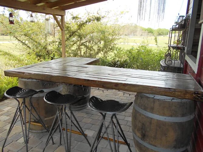 An outdoor wooden bar with tall stool chairs