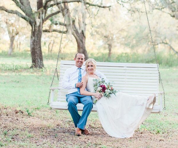 A wedding couple sitting on a white swinging bench